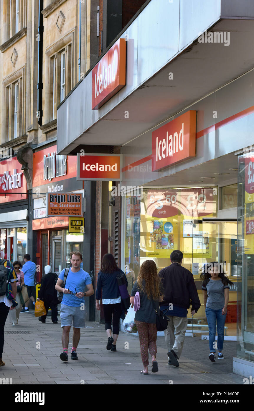 Le persone e gli amanti dello shopping a piedi passato indipendenti e negozi di beneficenza ed un ramo di Islanda, situato sulla Finchley Road High Street a Londra del nord. Foto Stock