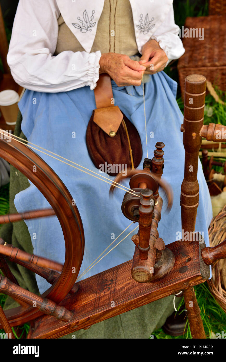 La donna nel XVII secolo il costume di filatura della lana naturale filettatura con ruota di filatura durante la Guerra Civile Inglese rievocazione storica Foto Stock