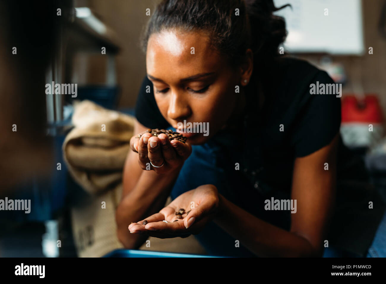 Donna di esame e odorare il profumo di caffè in chicchi dopo la tostatura Foto Stock