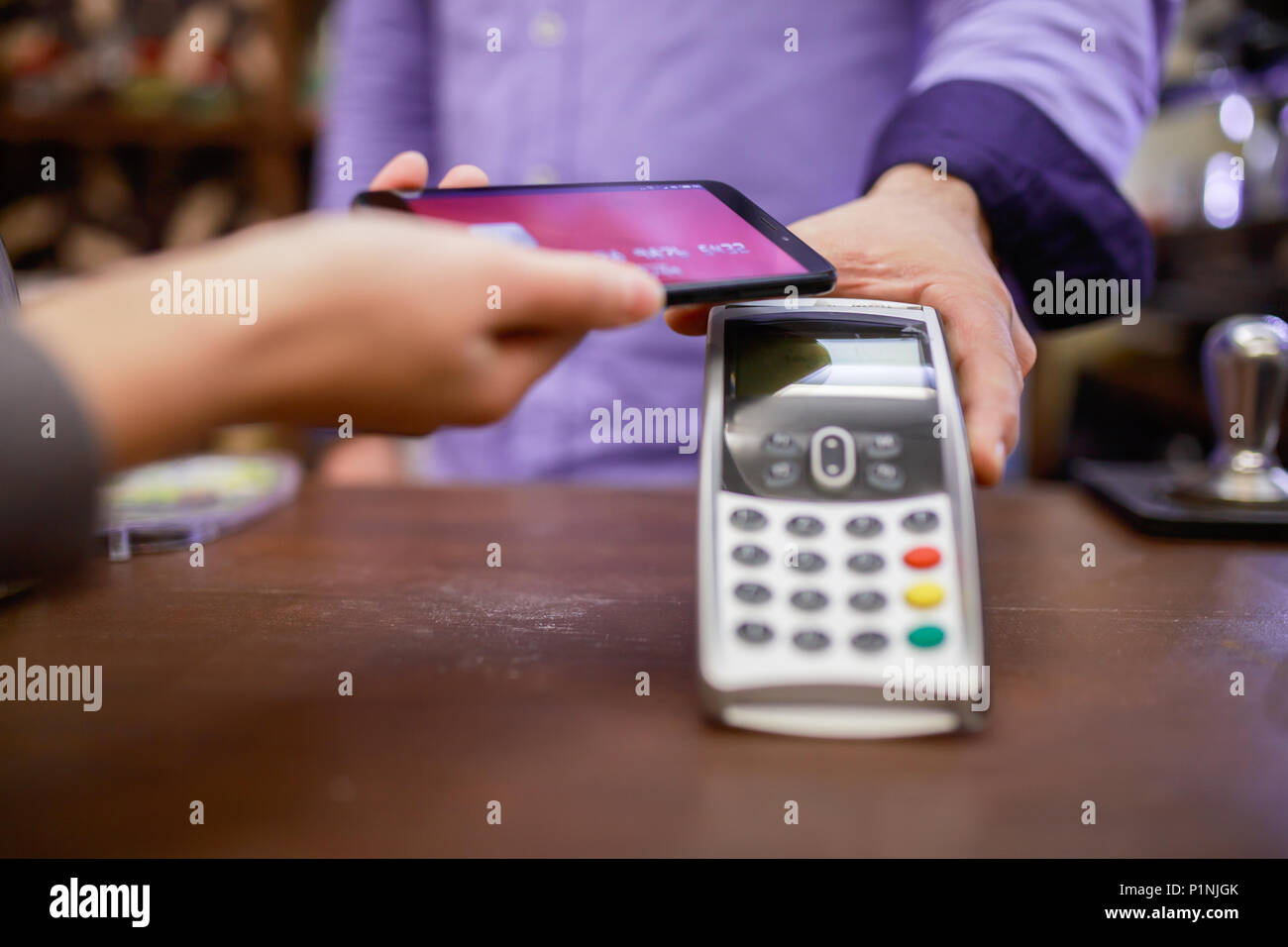 Immagine del venditore man con il terminale e il compratore con lo smartphone in negozio Foto Stock