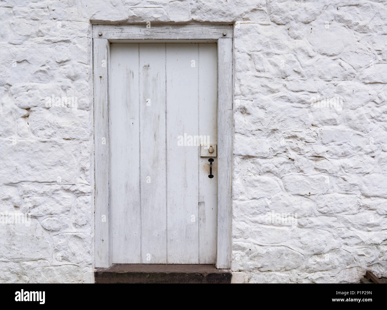 Vecchio weathered bianco porta in legno su un dipinto di bianco edificio di pietra Foto Stock