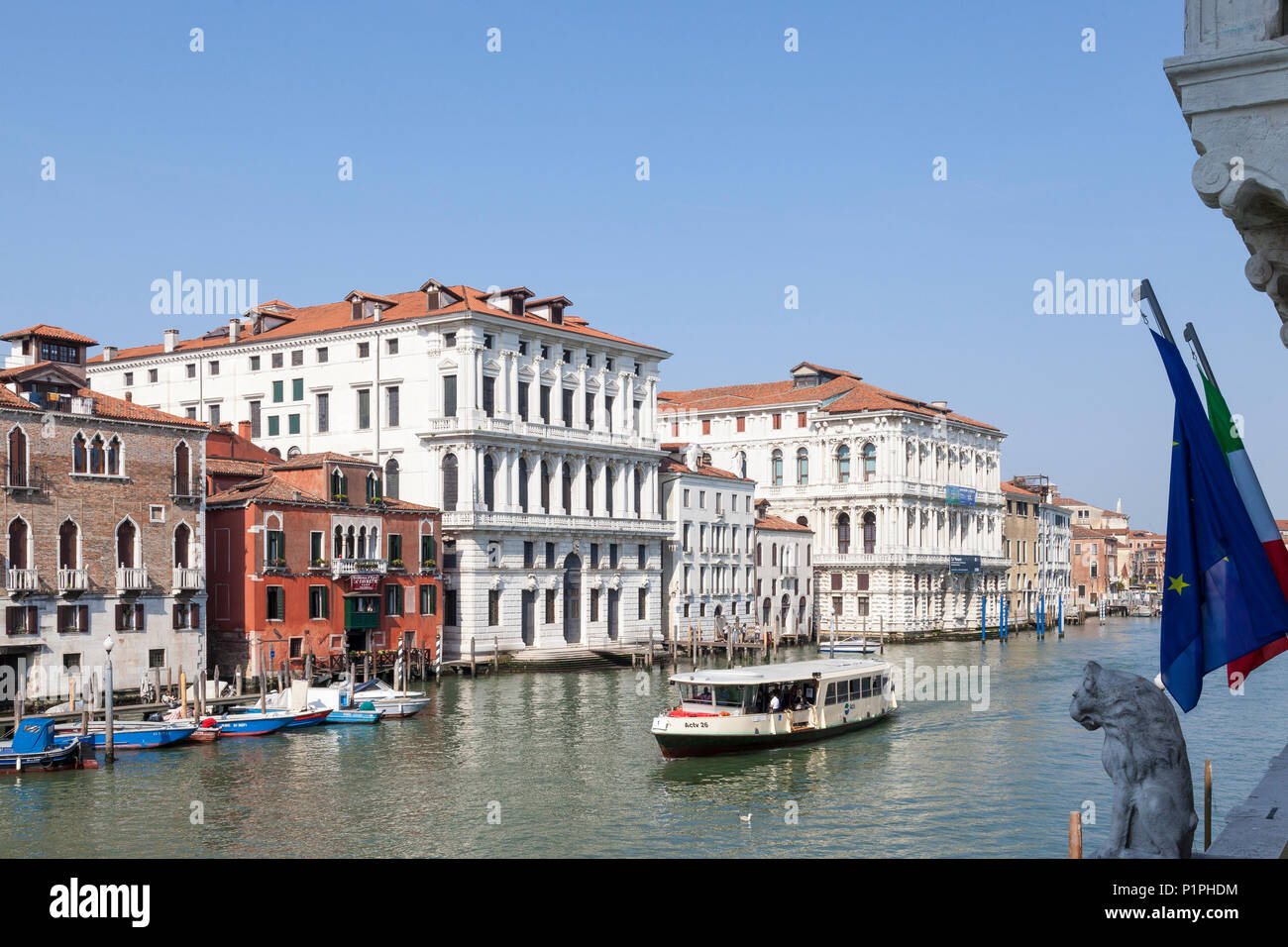 Vista in elevazione del Canal Grande con Ca'angolo della Regina e di Ca' Pesaro, Venezia, Italia con un vaporetto o vaporetto e statua di Lion e bandiere Foto Stock