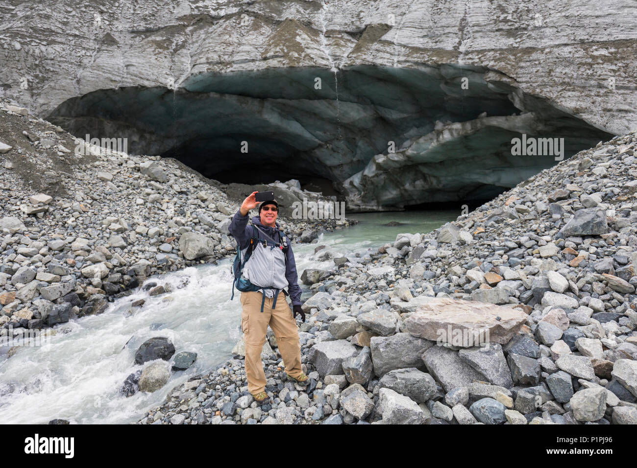 Escursionista maschio assume un autoritratto con il suo telefono cellulare nella parte anteriore di un ghiacciaio Gulkana caverna di ghiaccio;Alaska, Stati Uniti d'America Foto Stock