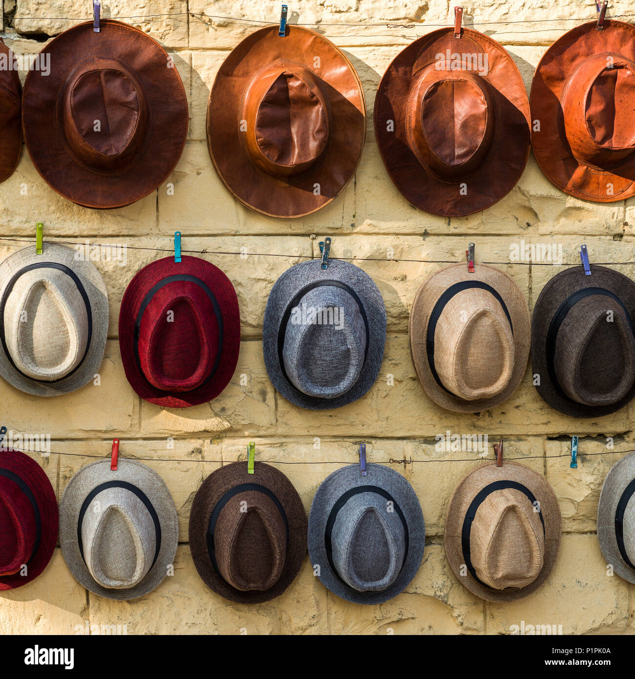 Vari stili di cappelli appesi in fila su una parete; Jaisalmer, Rajasthan, India Foto Stock