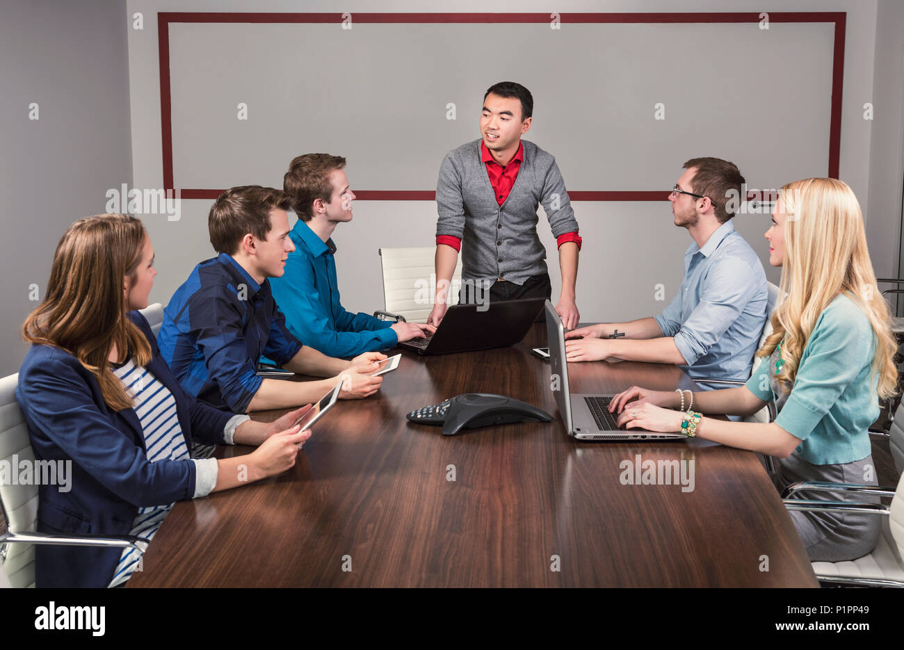 Giovani aziende millenario uomo parla a un gruppo di giovani professionisti in una sala conferenze in un luogo di affari; Sherwood Park, Alberta, Canada Foto Stock