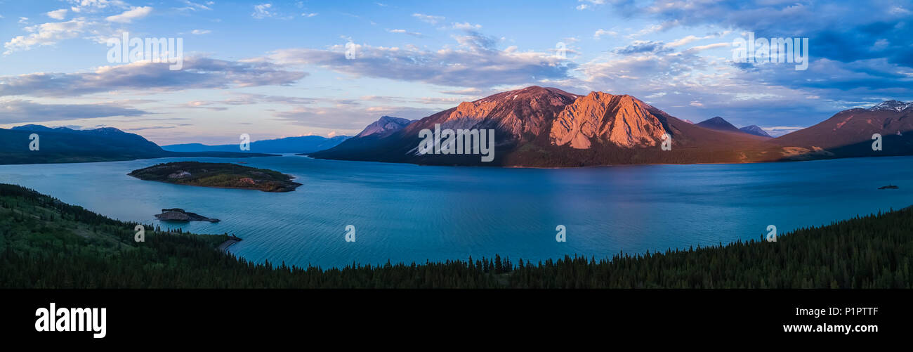 Dusky luce illumina le montagne circostanti il lago di Tagish nello Yukon; Carcross, Yukon Territory, Canada Foto Stock