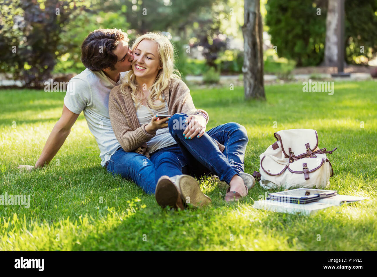 Una giovane coppia condivide un momento romantico insieme seduta sul prato del campus universitario; Edmonton, Alberta, Canada Foto Stock