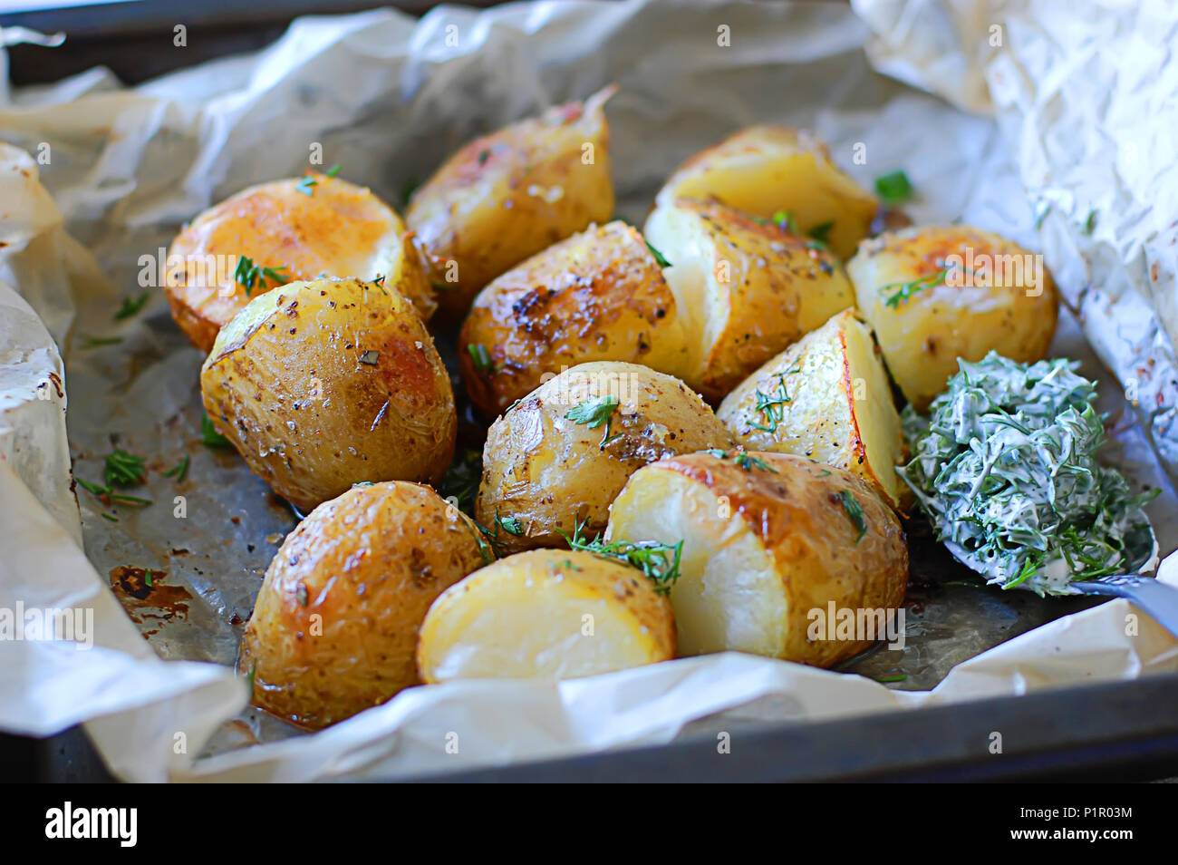 Patate fritte su vassoi da forno con crosta dorata e salsa di aneto Foto Stock