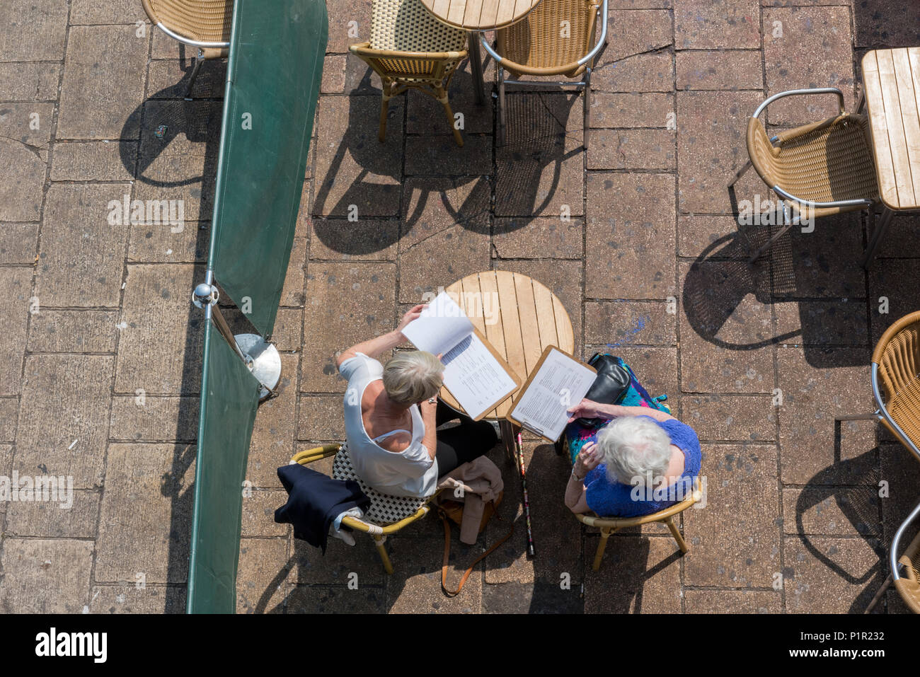 Due più anziani o persone anziane donne guardando un menu in un cafè sul lungomare di Brighton. guardando in giù su un sedie tavoli presso un ristorante sul lungomare di Brighton. Foto Stock