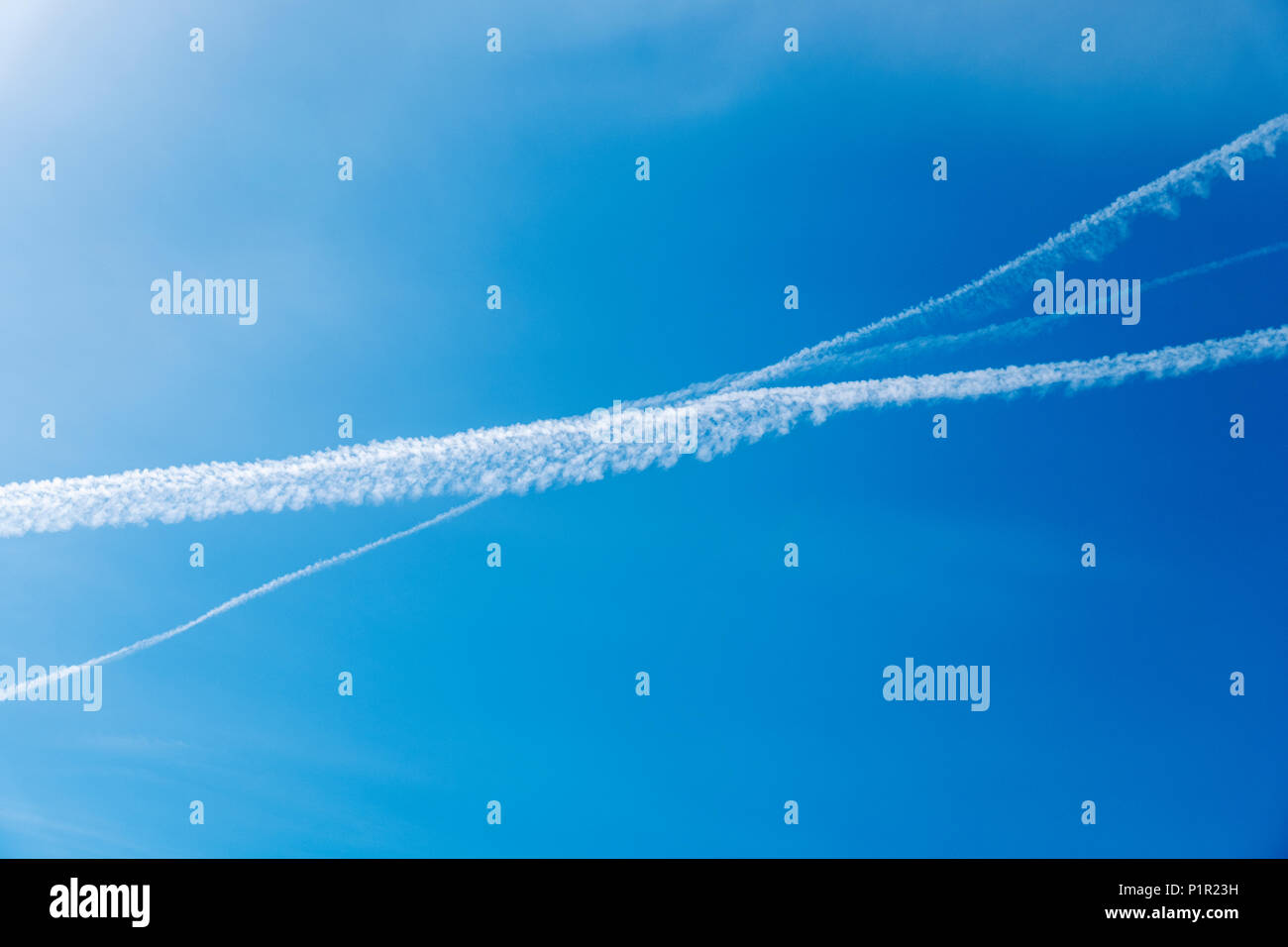 Jet contrails formano una X contro il colore azzurro del cielo azzurro Foto Stock