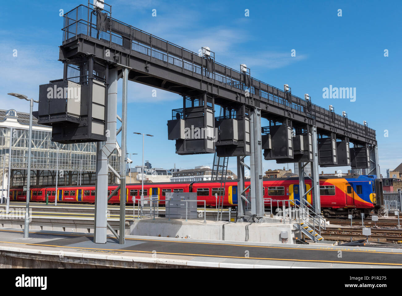 Un suburban commuter train azionato dail south western railway lasciando la stazione di Waterloo a Londra sotto una nuova segnalazione aggiornato il gantry. Foto Stock