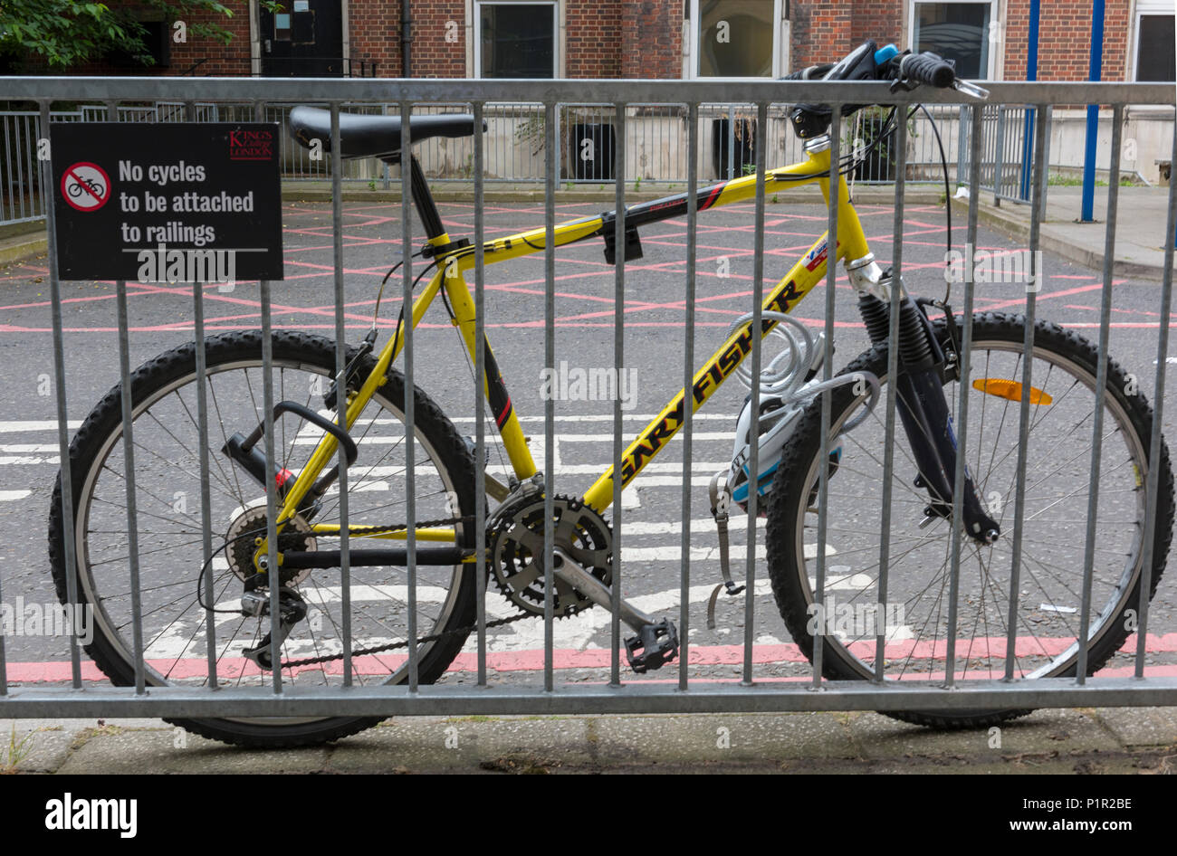 N. di cicli di essere concatenati per queste ringhiere divertente. Una bicicletta chiaramente violando la legge e facendo un baffo del cartello che vieta il parcheggio delle biciclette. Foto Stock