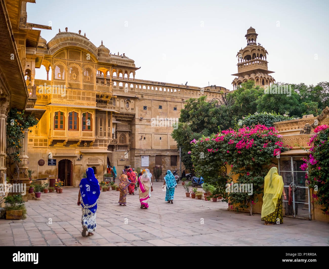 Le donne indiane a piedi in sari colorati in una piazza cittadina; Jaisalmer, Rajasthan, India Foto Stock