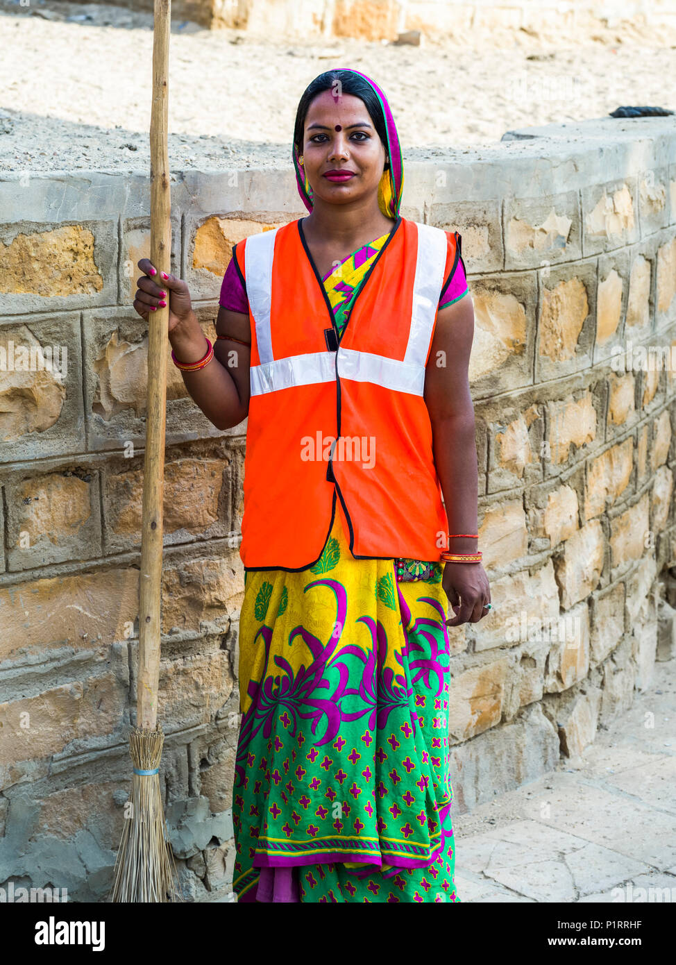 Ritratto di una donna indiana di indossare un giubbotto e tenendo una scopa; Jaisalmer, Rajasthan, India Foto Stock