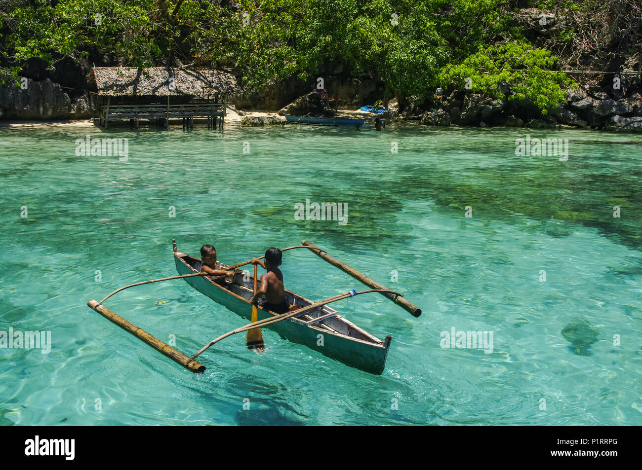 Ragazzi paddling in una canoa, pesca in acque turchesi dell'Oceano Indiano; Isole Andamane, India Foto Stock