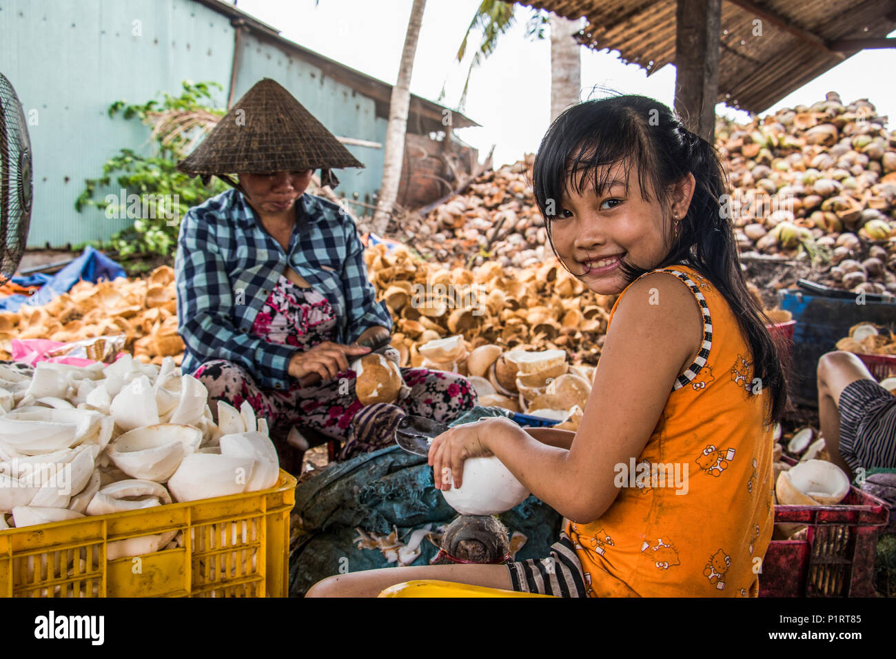 Ragazza e la donna in una elaborazione di cocco di proprietà familiare di nel Delta del Mekong, Ben tre, Vietnam Foto Stock