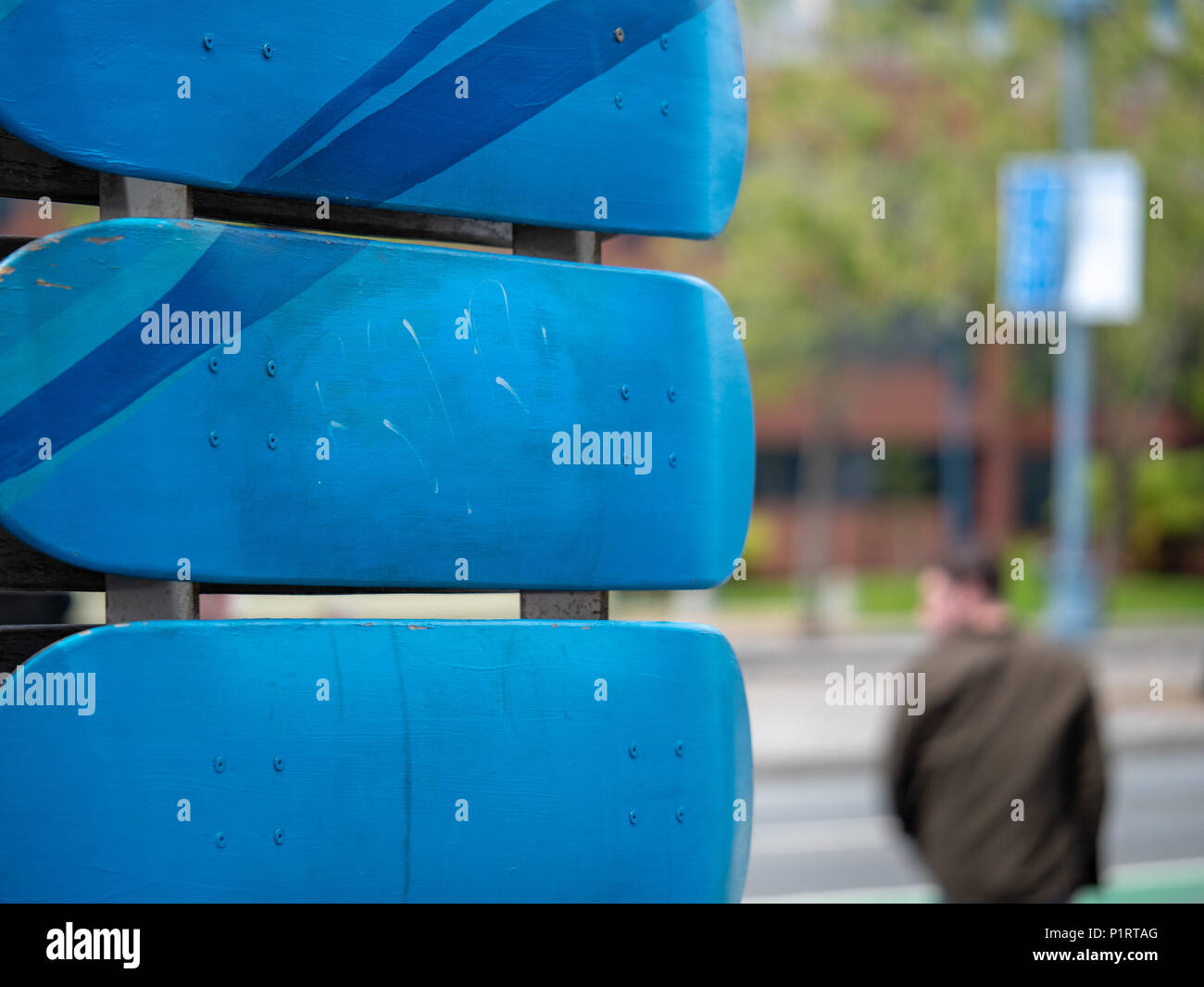 Una chiusura del blue deck skateboard montato con uomo a piedi in background Foto Stock
