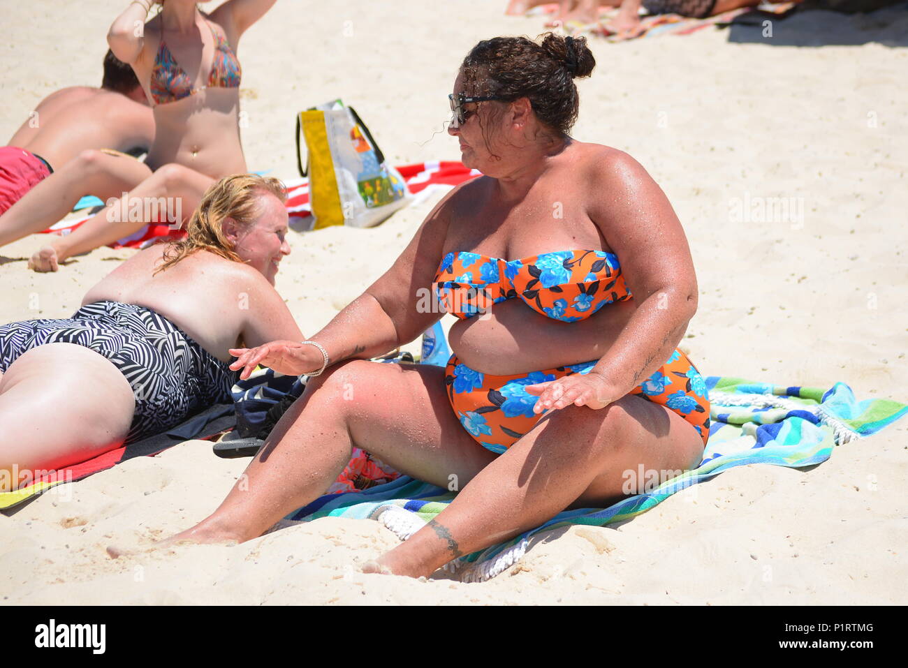 Un sovrappeso, plus donna dimensioni godendo di prendere il sole sulla spiaggia Foto Stock