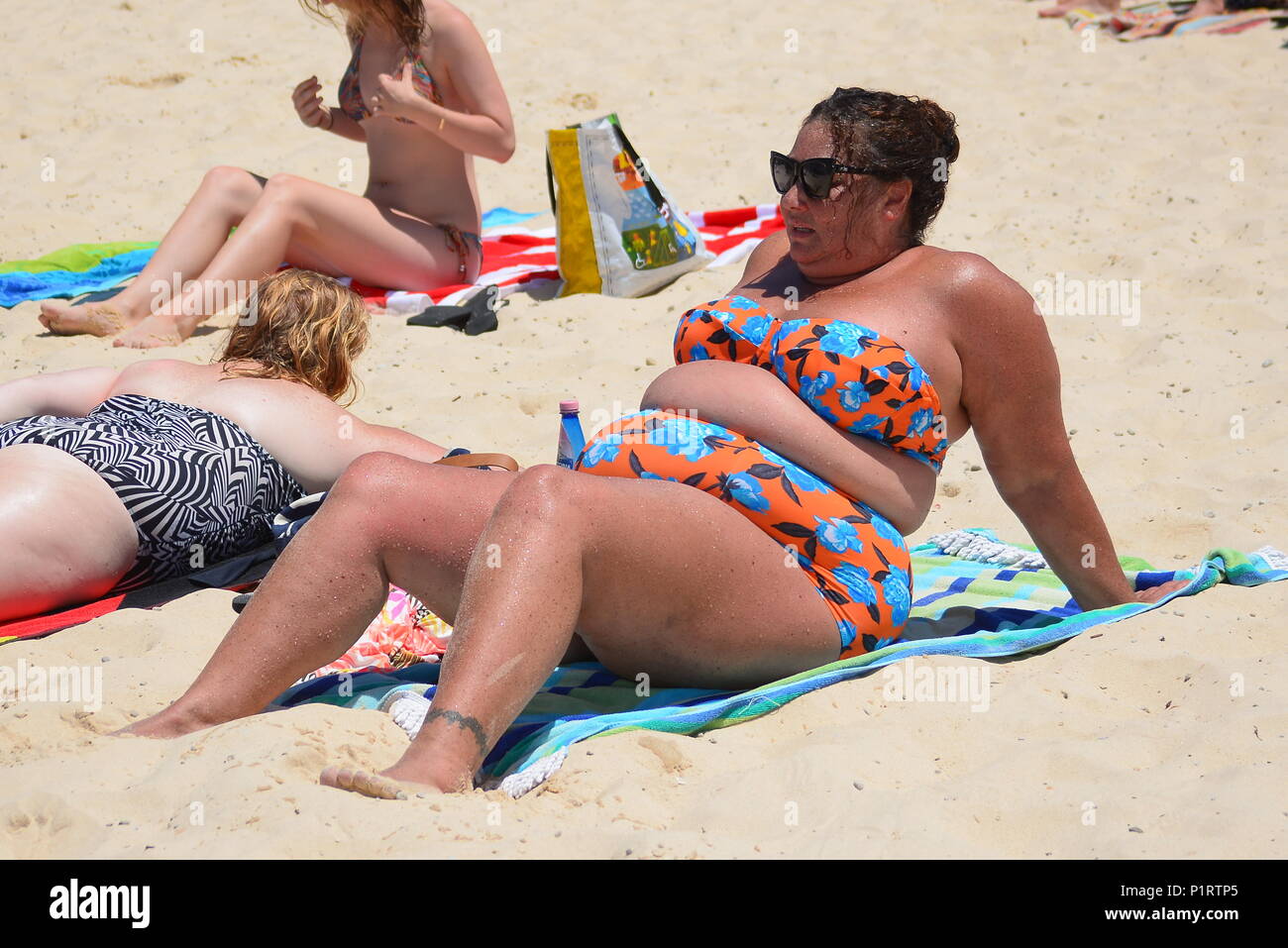 Un sovrappeso, plus donna dimensioni godendo di prendere il sole sulla spiaggia Foto Stock