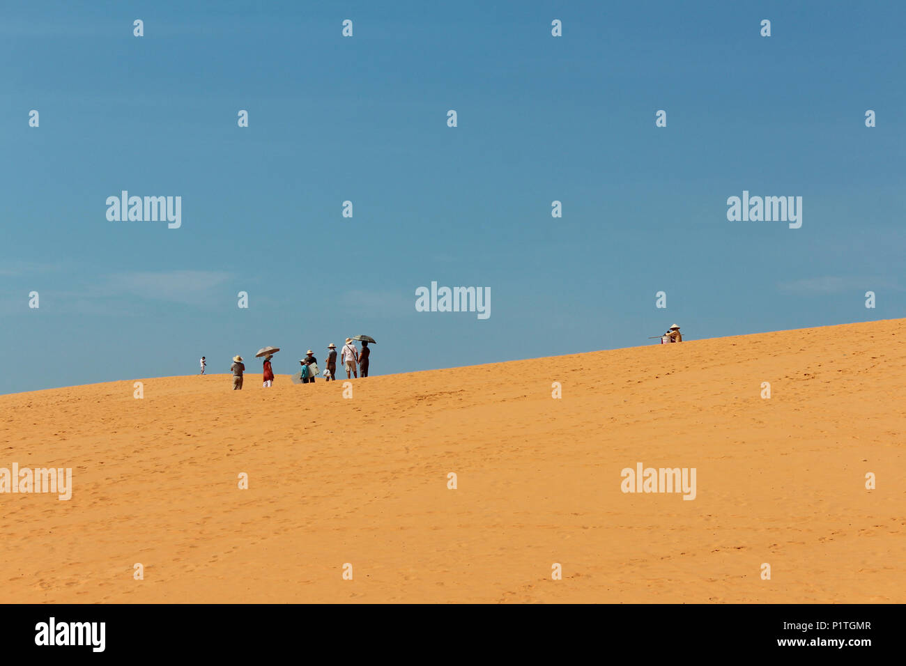 Mui Ne, Vietnam - Gennaio 2014: gruppo di turisti asiatici con ombrelloni nel paesaggio del deserto rosso / dune di sabbia di Mui Ne, Vietnam Foto Stock