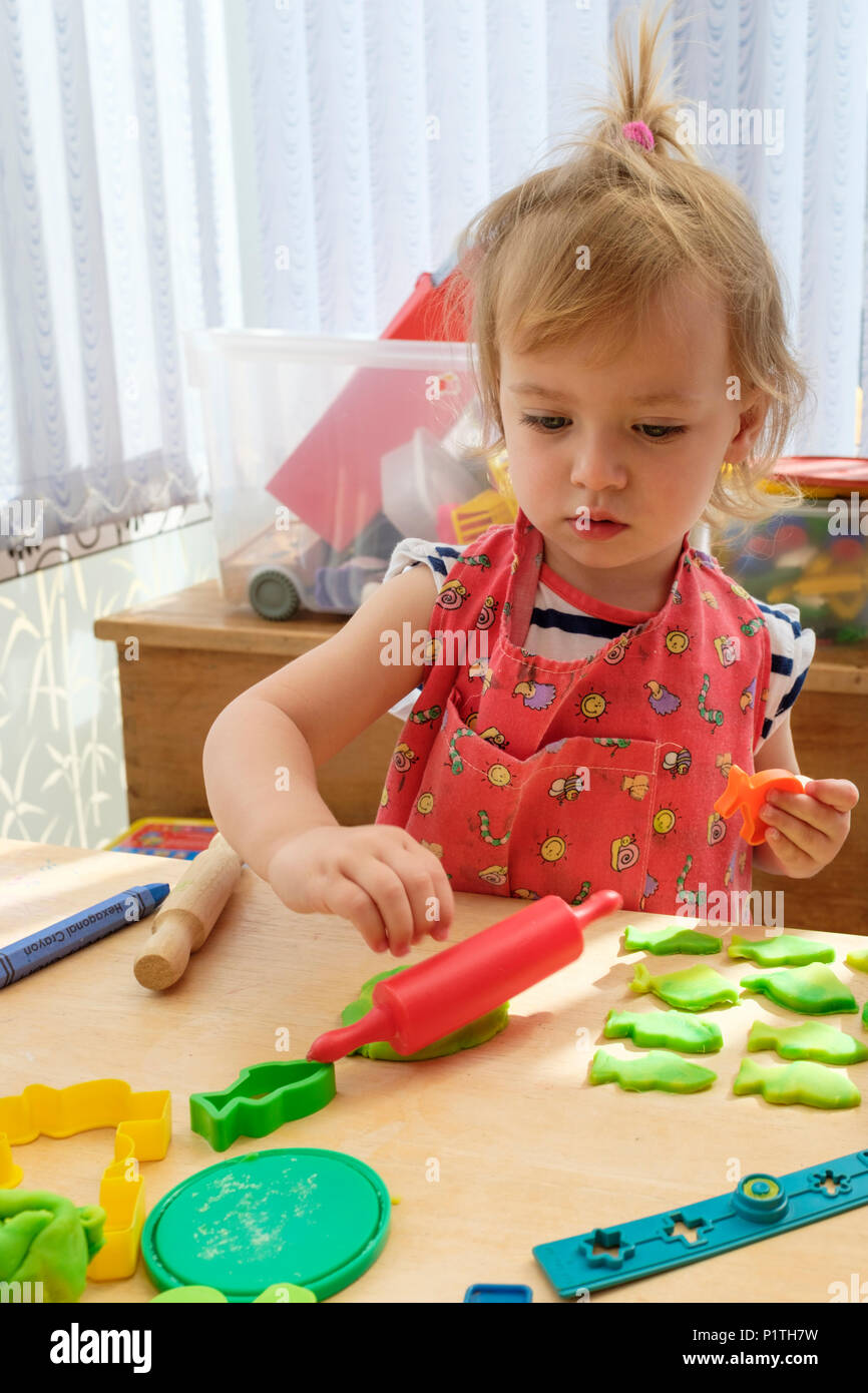 Imparare attraverso il gioco. Felice giovane ragazza di due anni che gioca e taglia fuori modellare l'argilla di pasta. Foto Stock