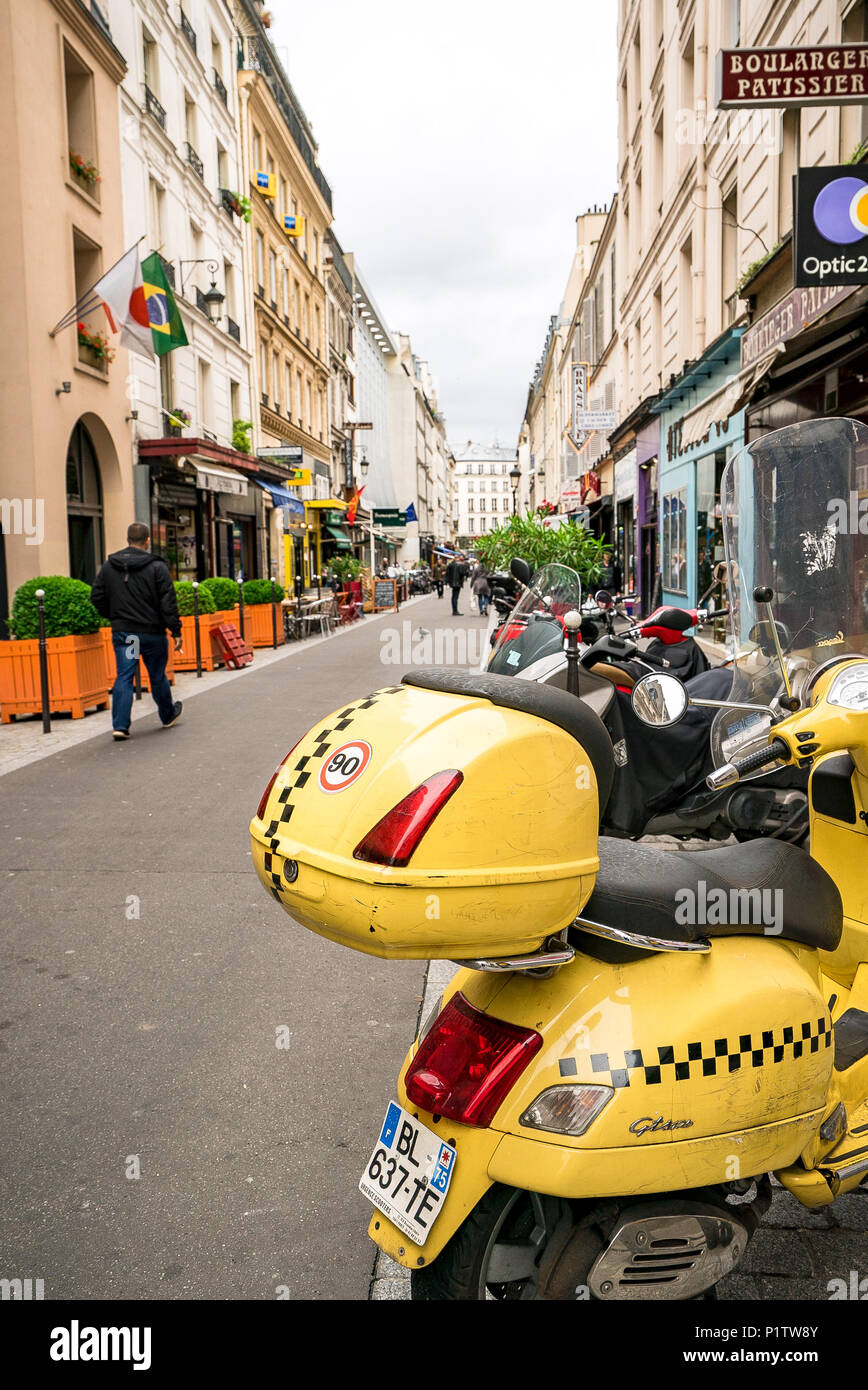 Un giallo brillante scooter parcheggiati sul lato di una strada di Parigi Foto Stock
