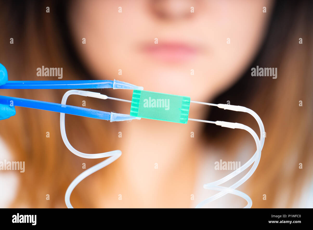 Il tecnico ragazza con dispositivo microfluidico LOC in laboratorio microbiologico Foto Stock
