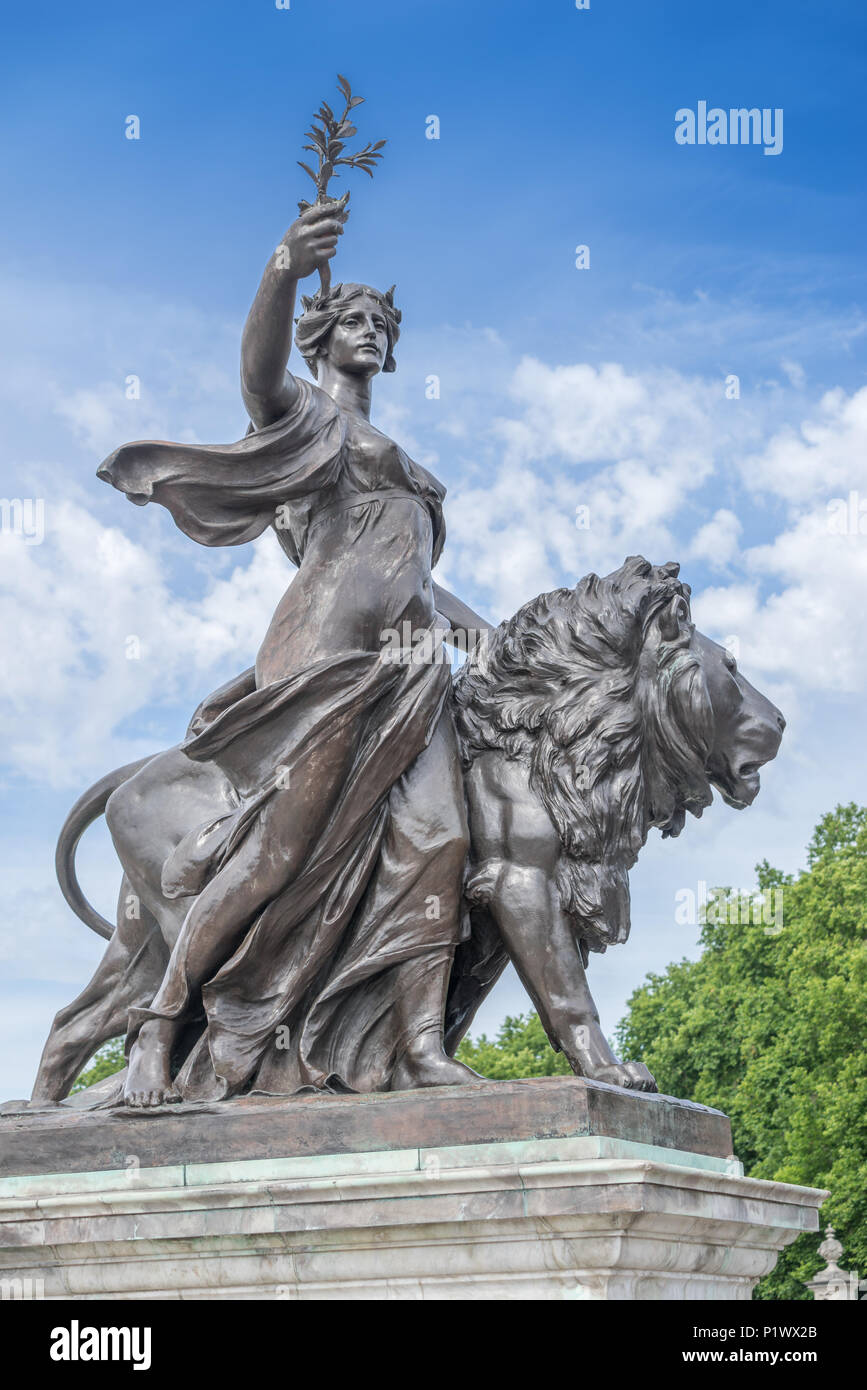 Uno dei quattro grandi leone di bronzo sculture, parte della regina Victoria Memorial di fronte a Buckingham Palace, mostra una donna che tiene un'oliva crusca Foto Stock