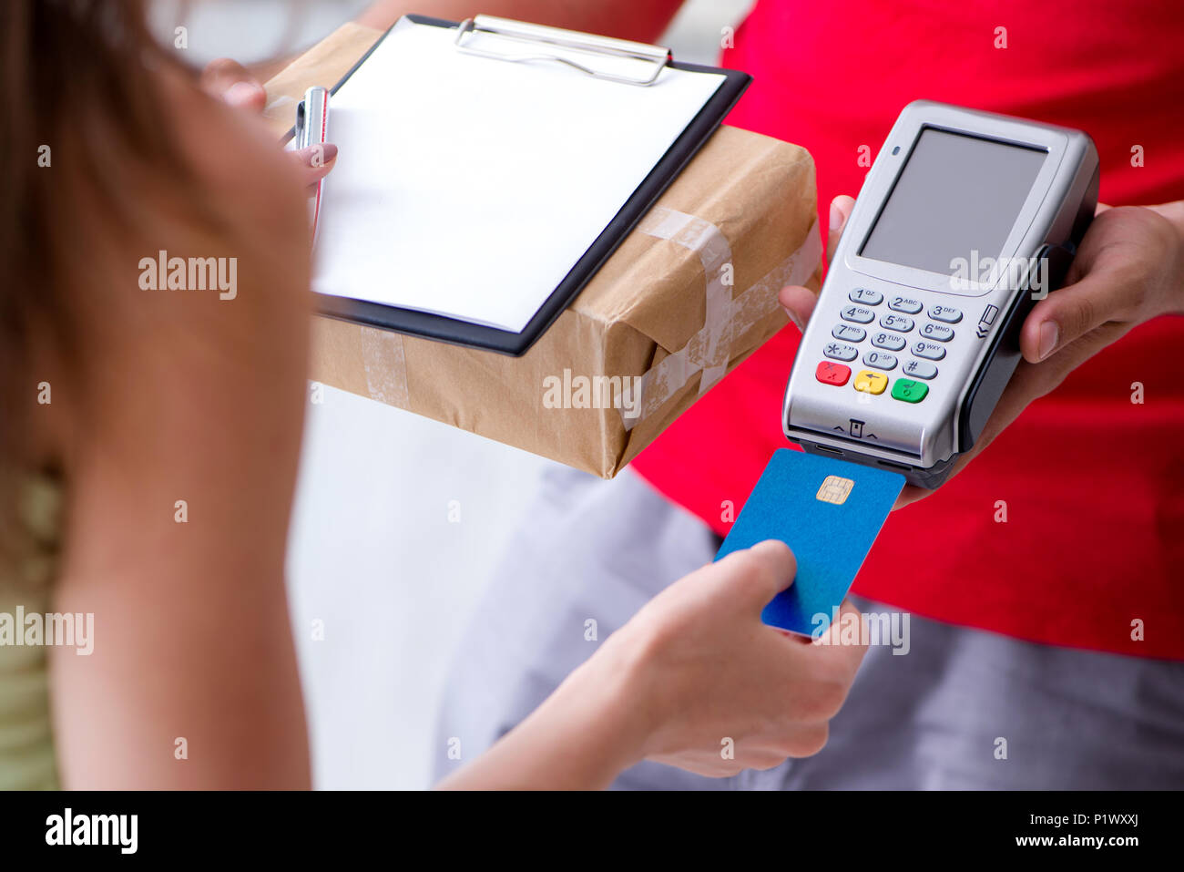 La consegna di pacchi essendo pagato con pos e carta di credito Foto Stock