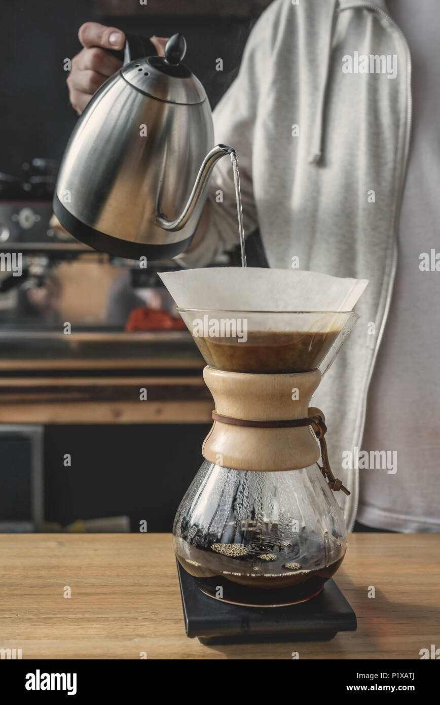 Close-up di un irriconoscibile barista versando acqua calda in chemex. La preparazione del caffè concept Foto Stock