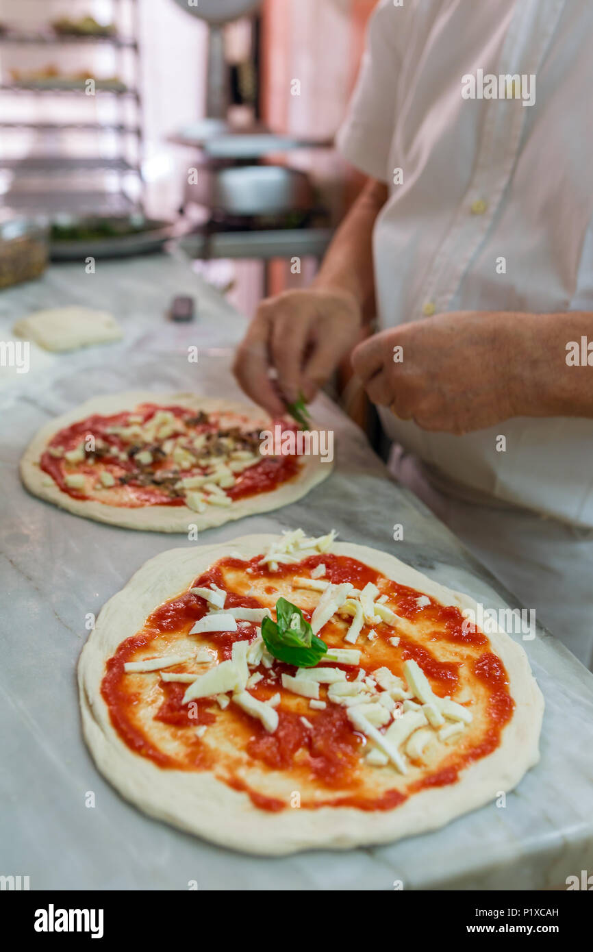 La preparazione di classic pizza Margherita in pizzeria tradizionale a Napoli, Italia. Messa a fuoco selettiva Foto Stock