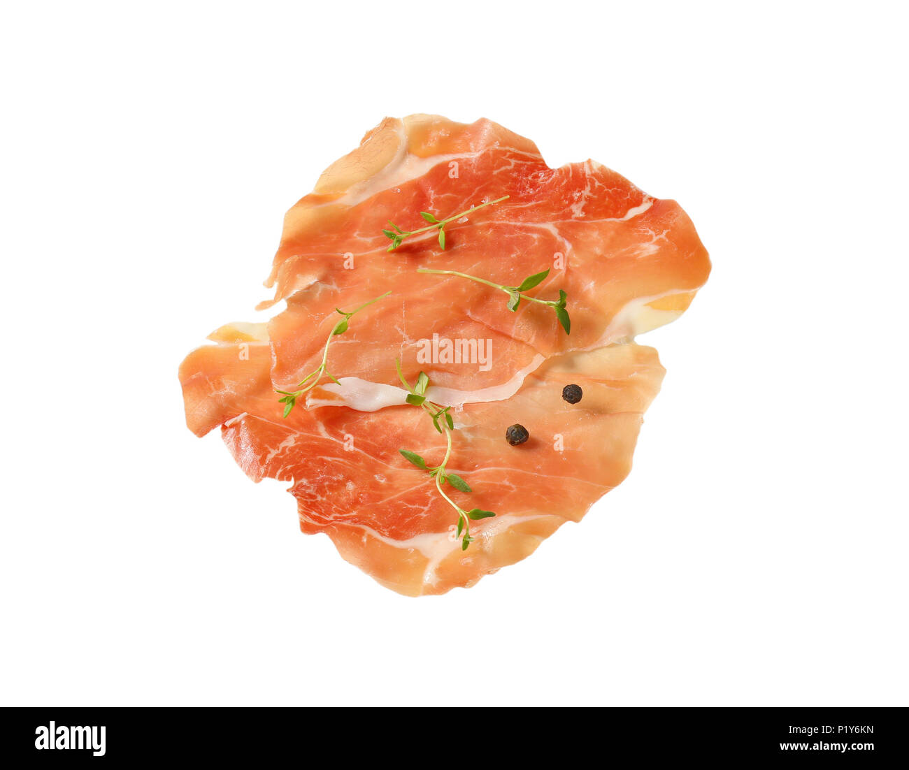 Fette di aria essiccata prosciutto con il timo e il pepe su sfondo bianco Foto Stock