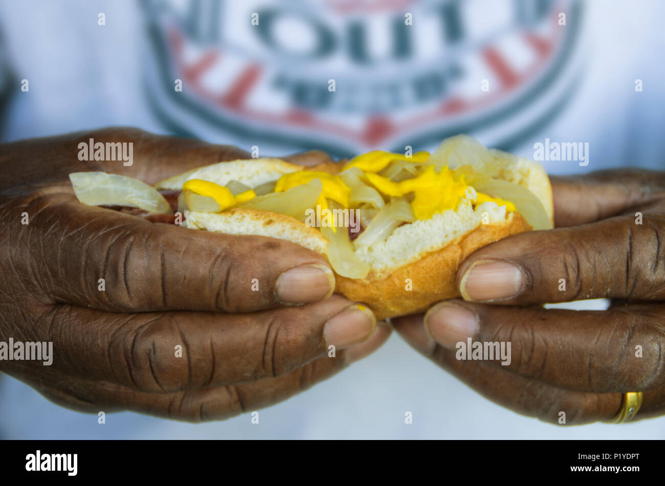 Un uomo diventa pronto per goderti un hot dog a neighboorhood celebrazione su National Night Out Foto Stock