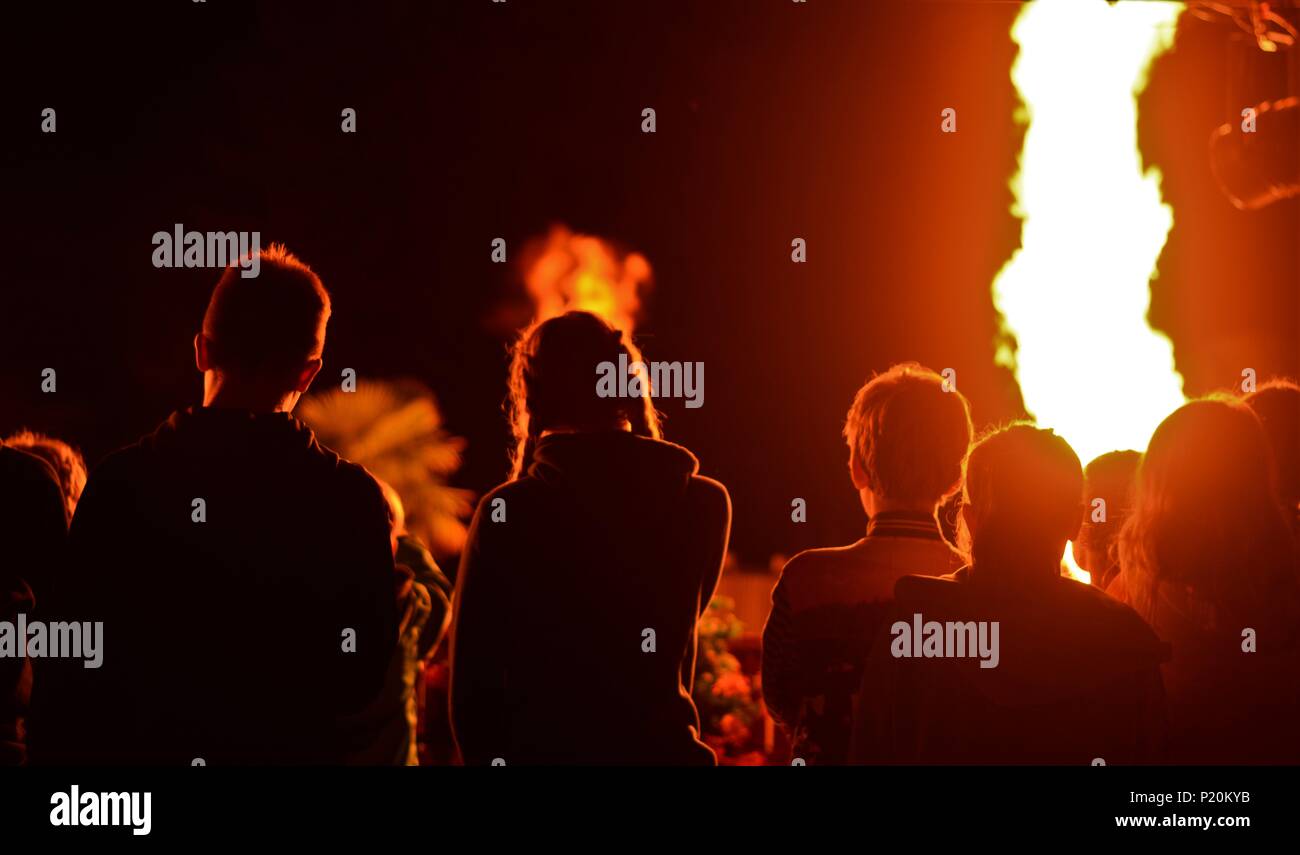 Un gruppo di giovani che frequentano un tempo di notte il fuoco e fuochi d'artificio in Bretagna, Francia Foto Stock