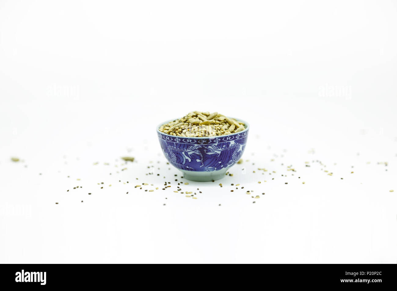 Piccolo vaso blu con semi di girasole, di sesamo e di chia su sfondo bianco con spazio di copia Foto Stock