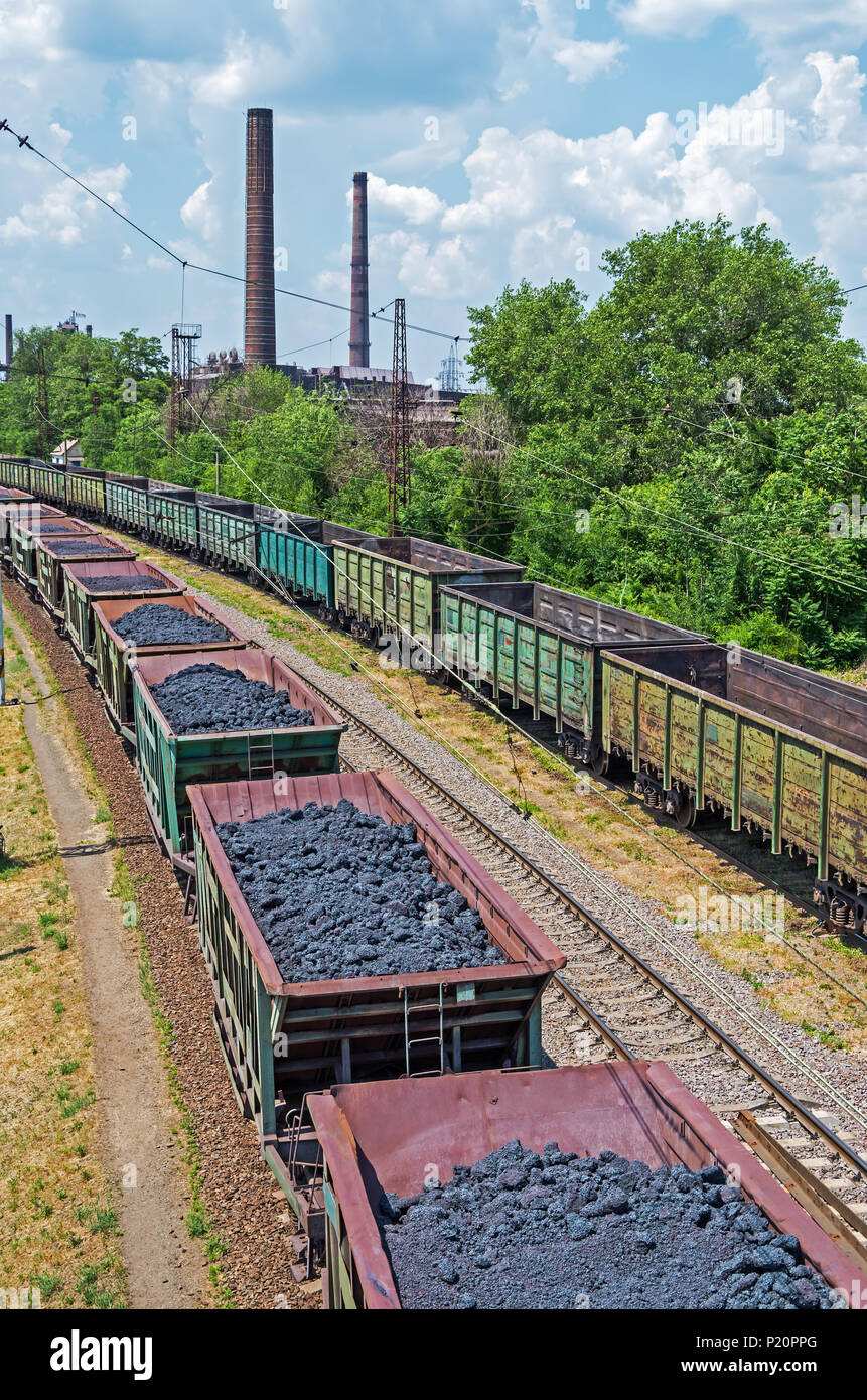 Carri merci con coke sui binari ferroviari che portano alla impresa metallurgica di altoforno smelting Foto Stock