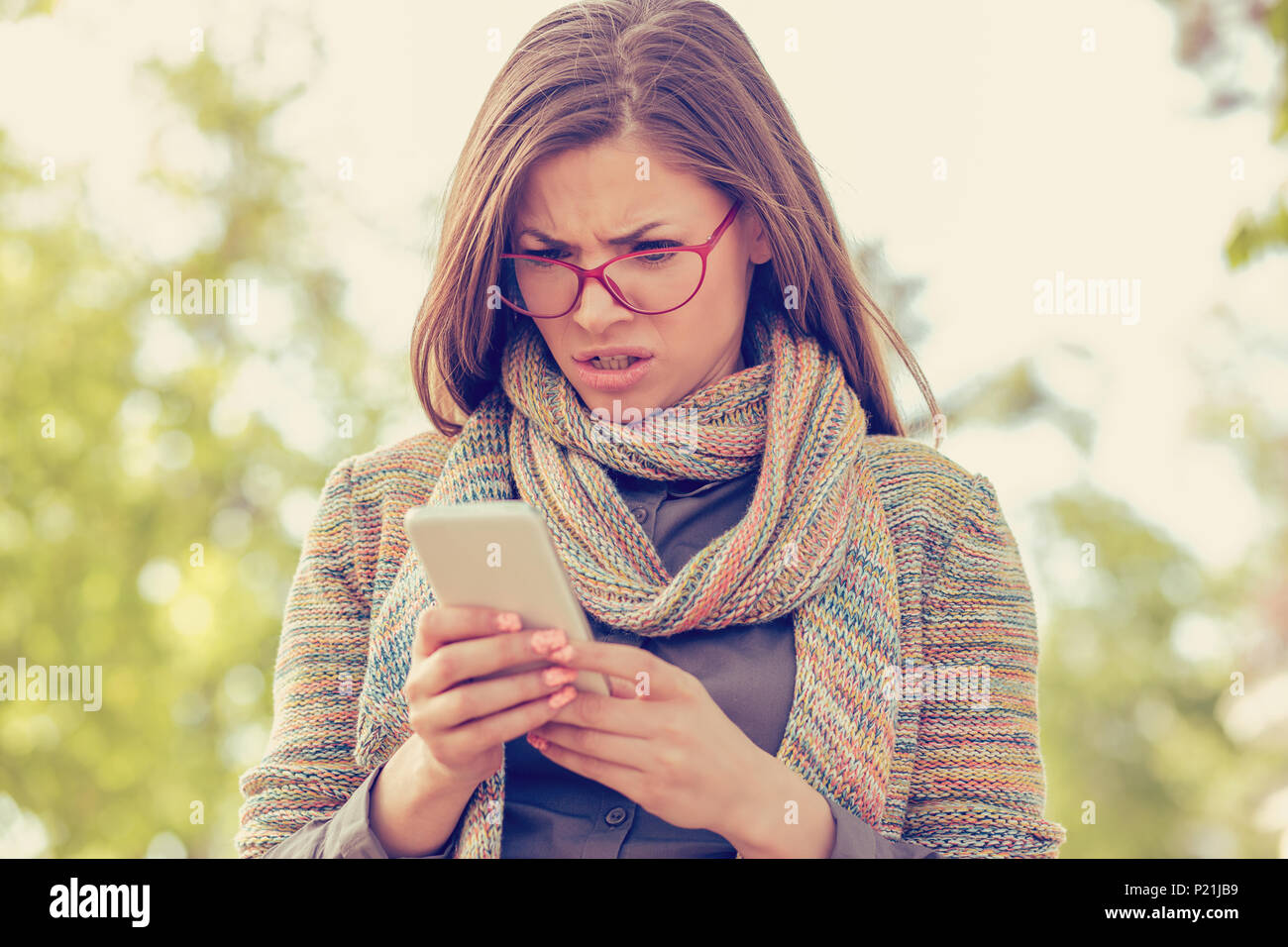 Donna che guarda arrabbiato con il telefono Foto Stock