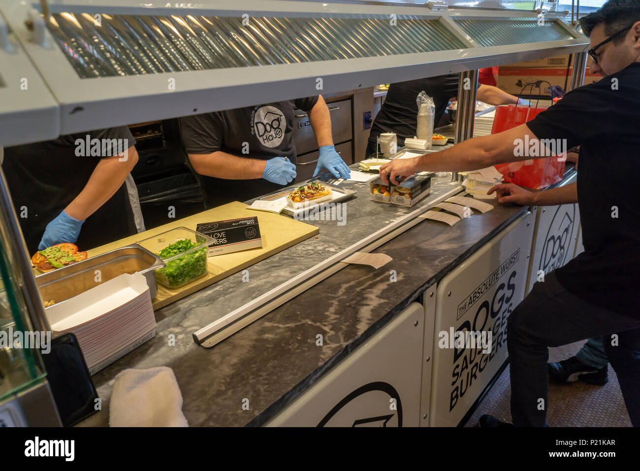 Gli ordini vengono preparati al cane Haus il giorno di apertura del loro primo negozio a New York martedì, 12 giugno 2018. I visitatori sono stati trattati per un servizio gratuito di hot dog come un benvenuto alla loro posizione più recente di Soho. La catena è specializzata in fast pasti informali di hot dogs, salsicce, pollo e hamburger alla griglia su re rotoli Hawaiiano e guarnita con la loro firma 'Crea'. Cane Haus fu fondata nel 2010 a Pasadena, Caifornia con piani di aprire 300 nuovi franchising dal 2023. (© Richard B. Levine) Foto Stock