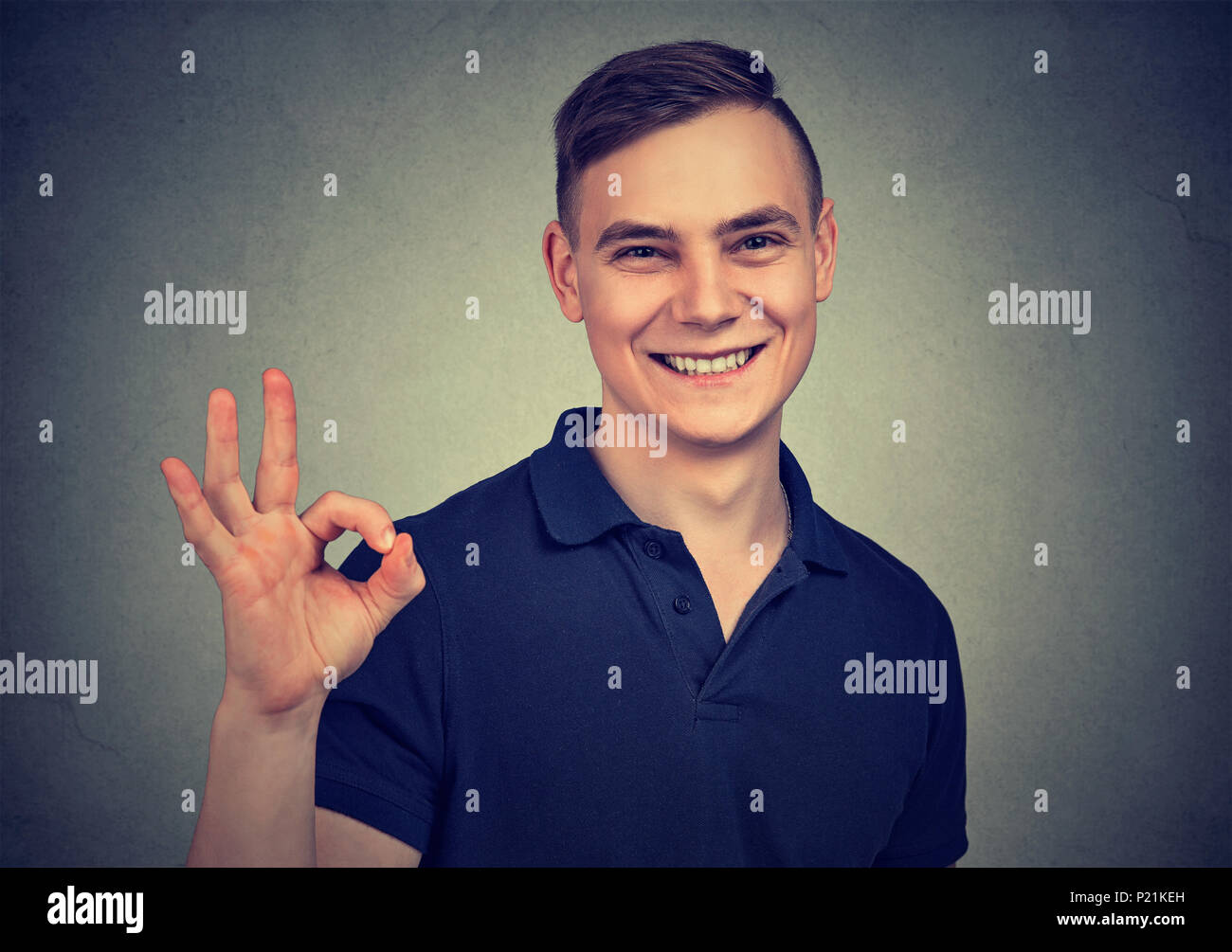 Uomo bello che mostra ok segno isolato su sfondo grigio Foto Stock