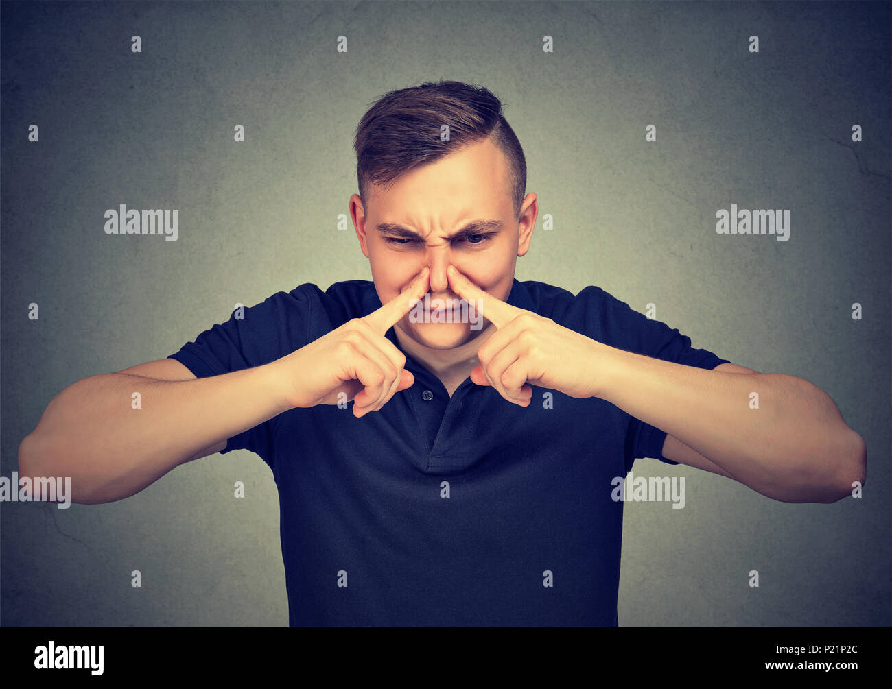 L'uomo pizzichi di naso con le dita guarda con disgusto Qualcosa puzza isolato su sfondo grigio. Foto Stock