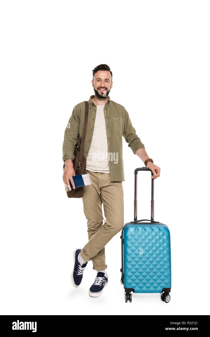 Uomo sorridente con la valigia e borsa azienda biglietto di viaggio e passaporto in mano isolato su bianco Foto Stock
