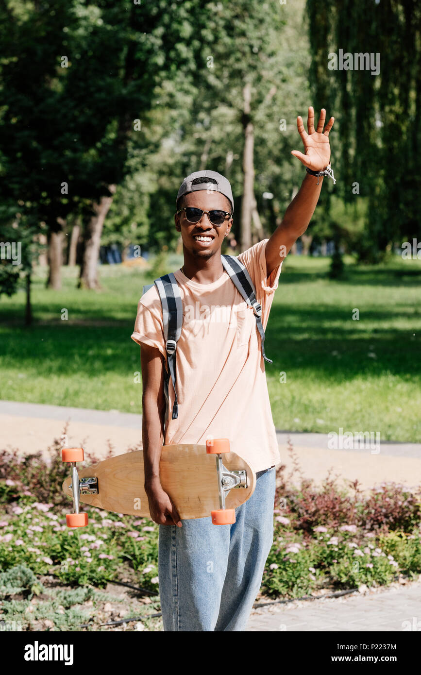Elegante African American uomo con braccio teso holding longboard Foto Stock