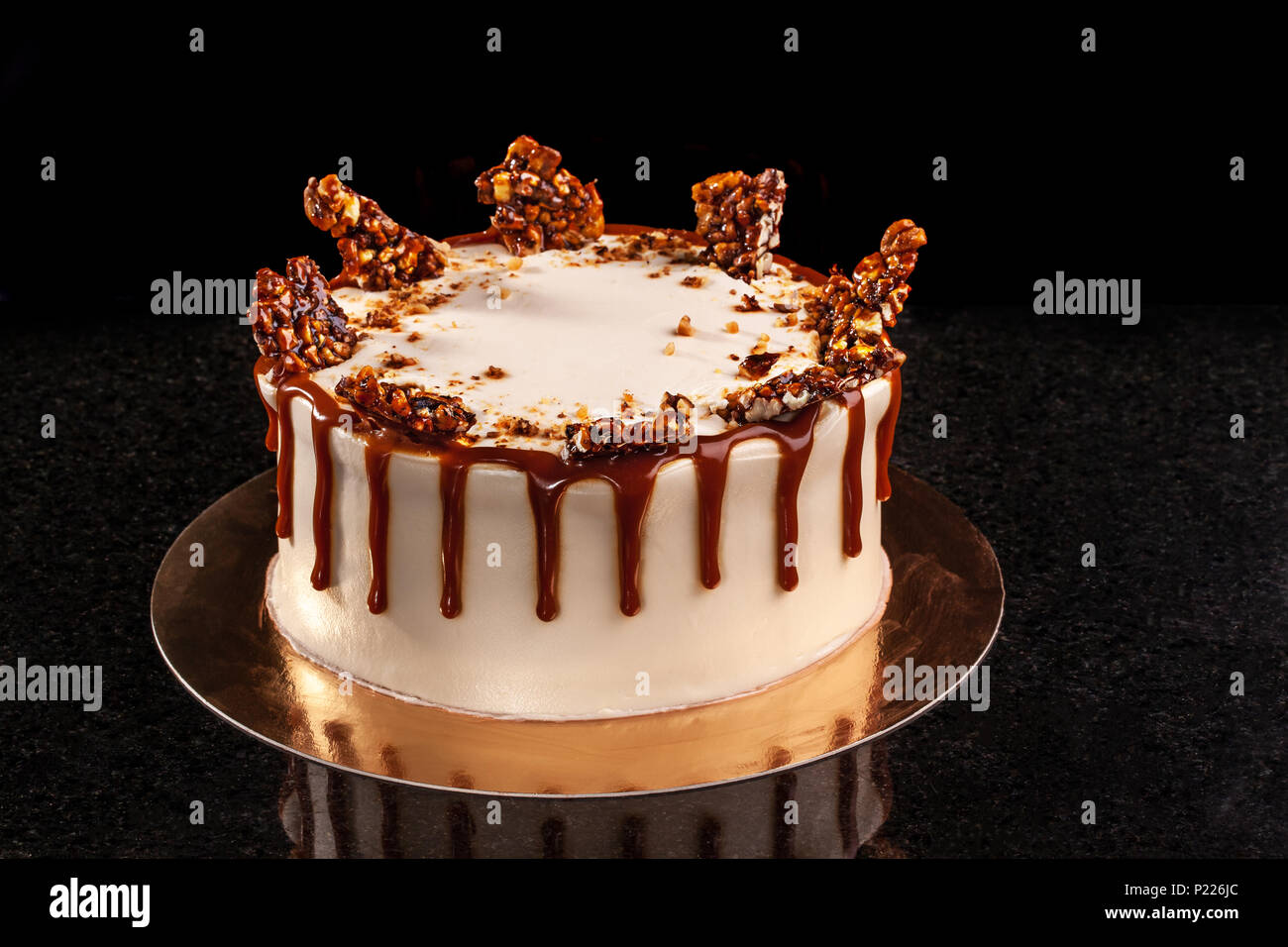 Bianco rotondo torta con caramello e cioccolato riso soffiato su un vassoio  rotondo su sfondo nero Foto stock - Alamy