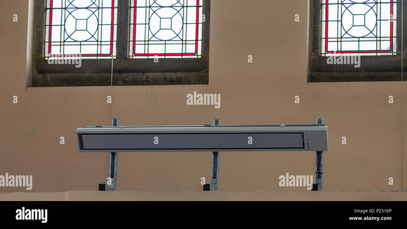 Un riscaldamento a infrarossi lontani pannello in una chiesa edificio. Foto Stock