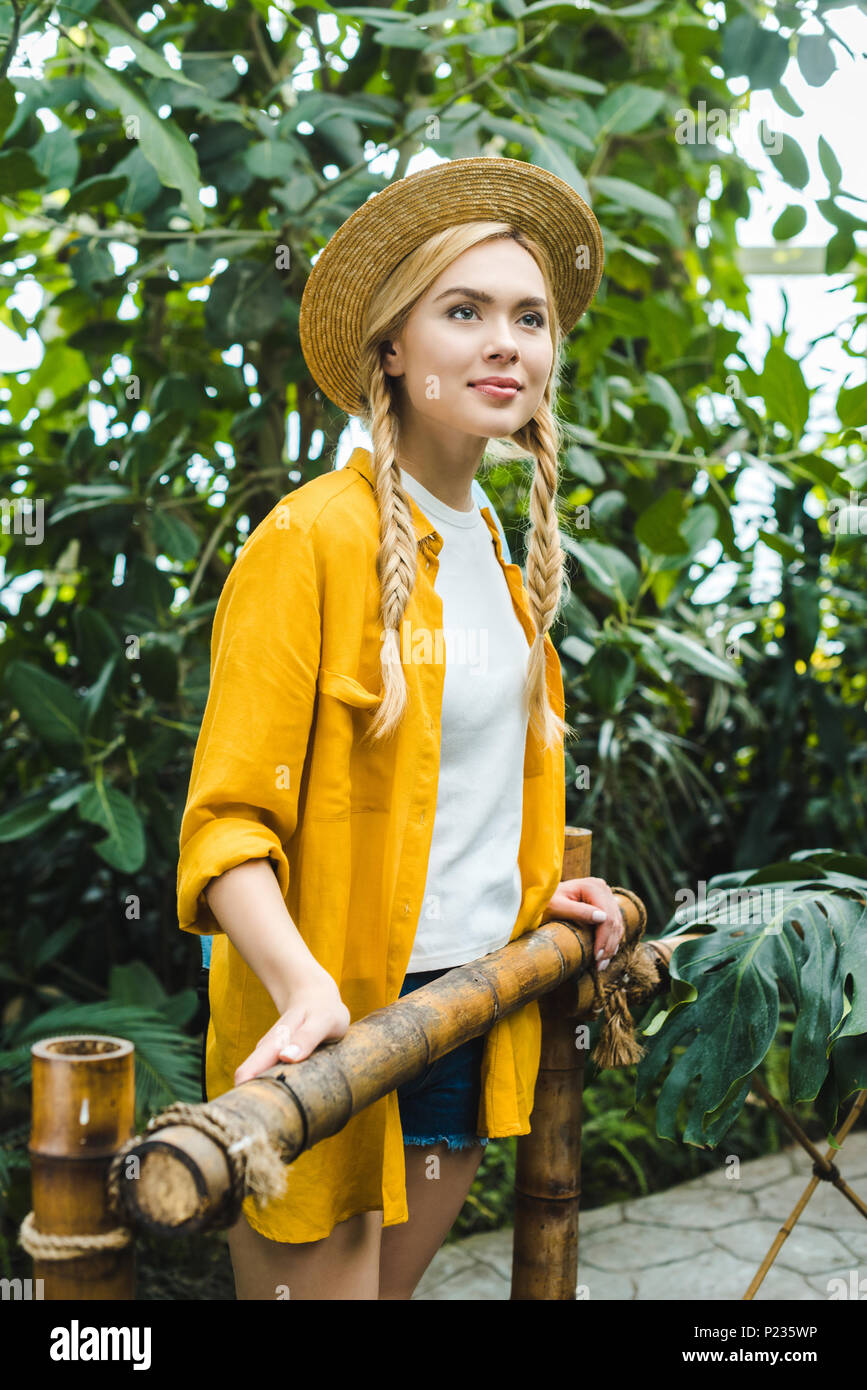 Attraente giovane donna nel cappello di paglia di trascorrere del tempo in giardino botanico Foto Stock