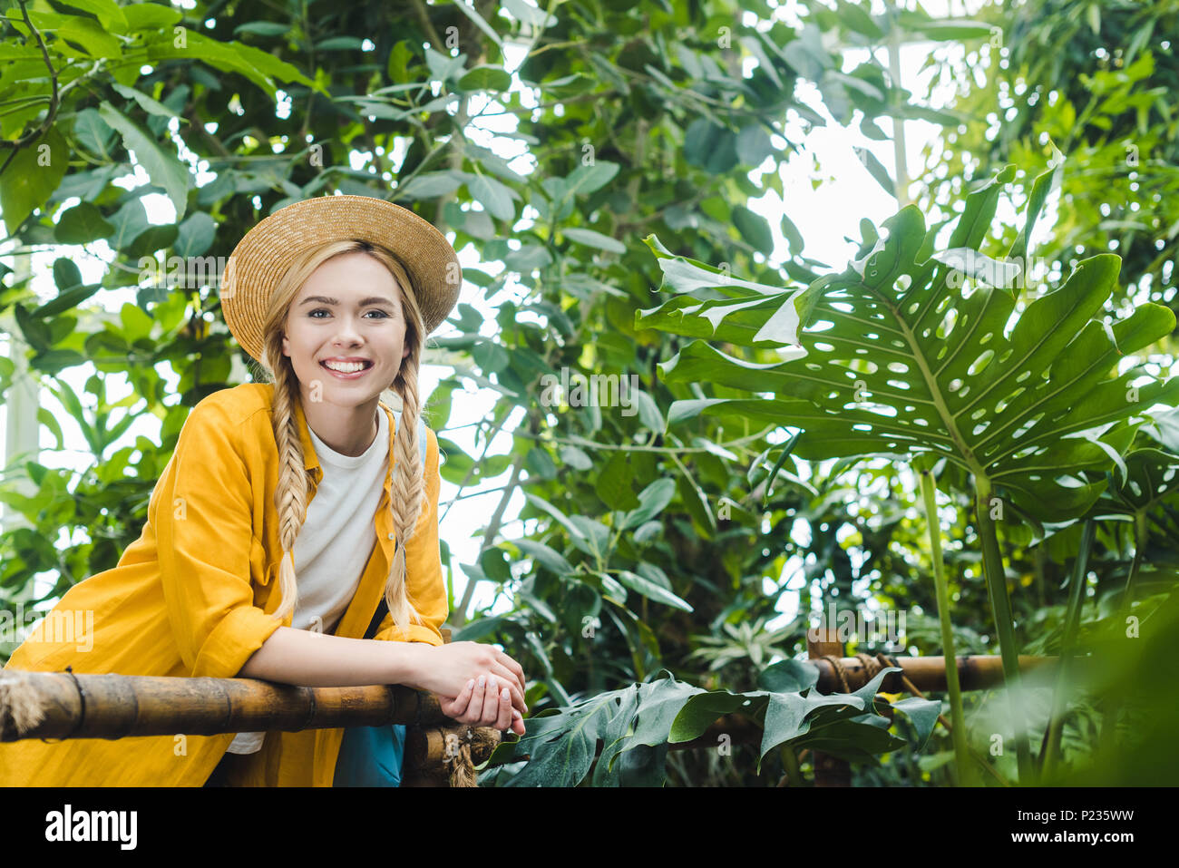 Bella giovane donna nel cappello di paglia di trascorrere del tempo in giardino botanico Foto Stock