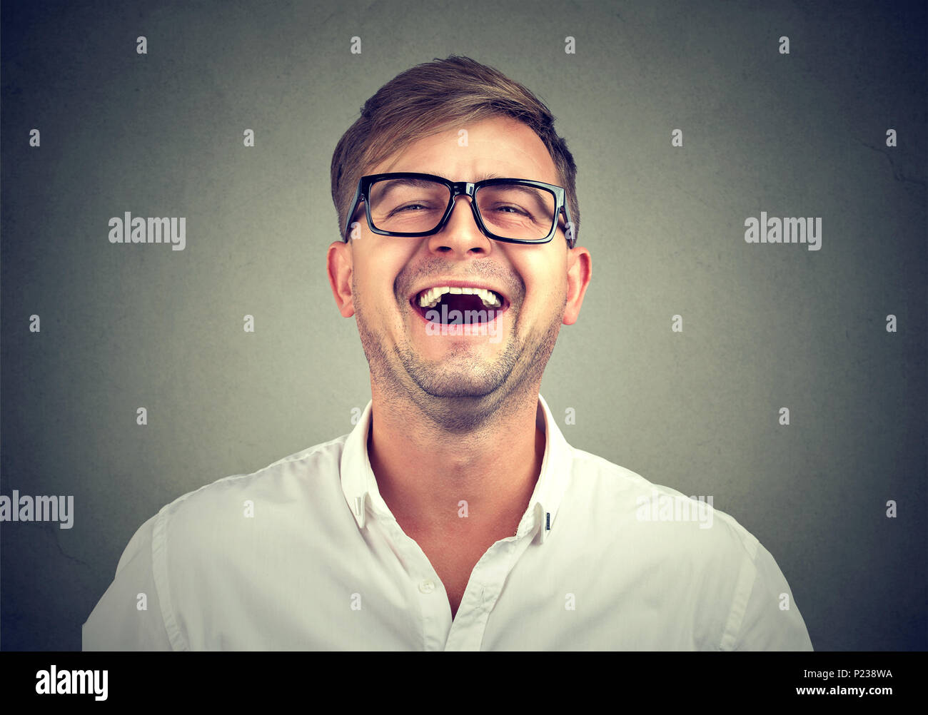Causale da giovane uomo in camicia bianca e occhiali neri ridere dal divertente scherzo. Foto Stock