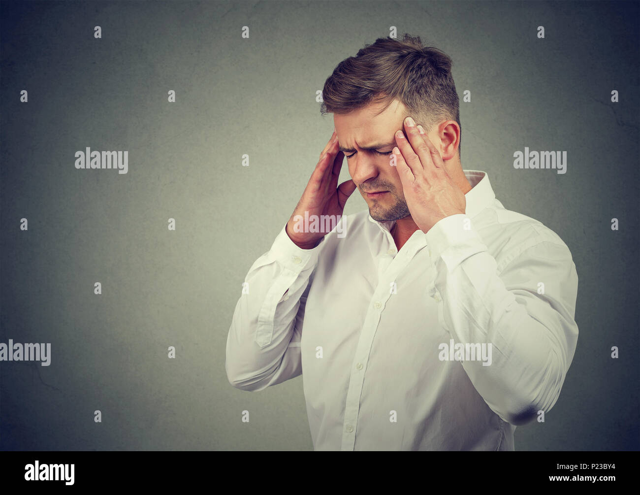 Giovane uomo templi di sfregamento con gli occhi chiusi e accigliata da mal di testa e ansia. Foto Stock