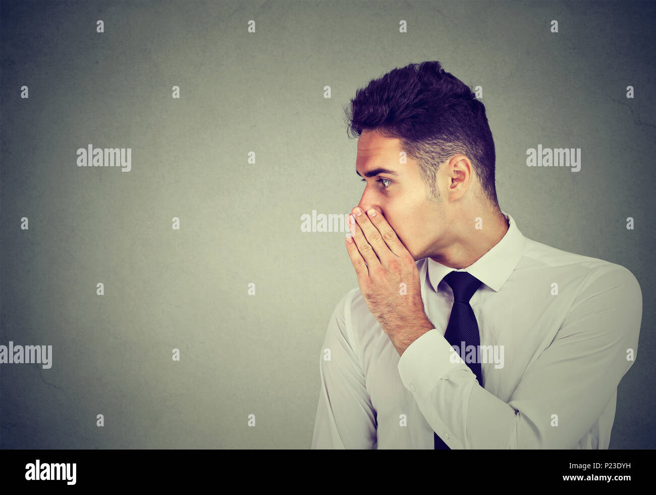 Business man sussurra un segreto di pettegolezzo a qualcuno isolato su sfondo grigio Foto Stock