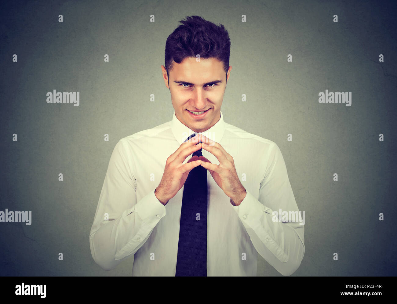 Subdolo intrigante uomo che cerca di tracciare qualcosa di isolato su sfondo grigio. Negativo emozione umana espressione facciale sensazione Foto Stock